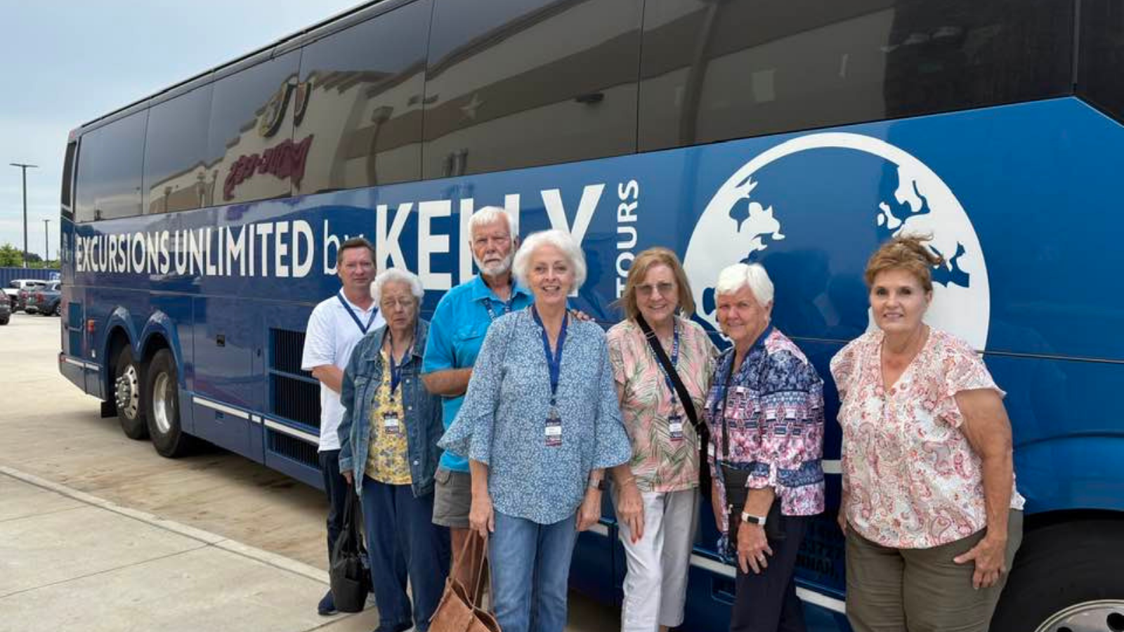 group of travelers standing in front of a Kelly Tours charter bus