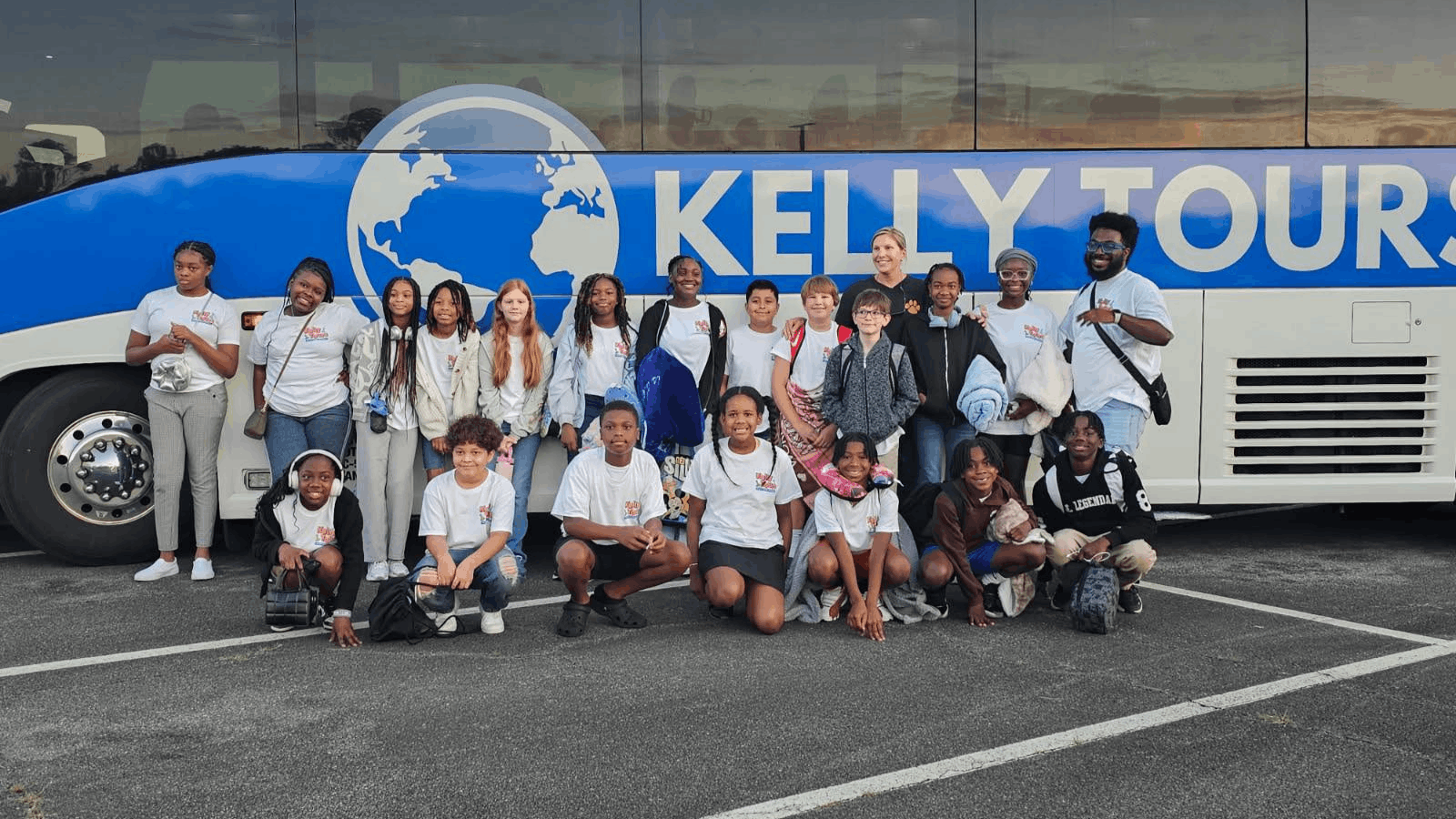 group of students in front of a kelly tours charter bus for a student trip